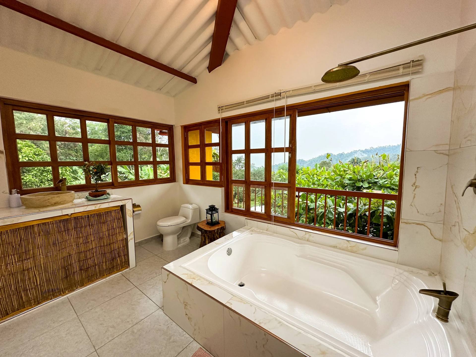 Bathroom with oversized bath, stone sink and a window looking onto the mountains (King Suite, El Nido Andino)
