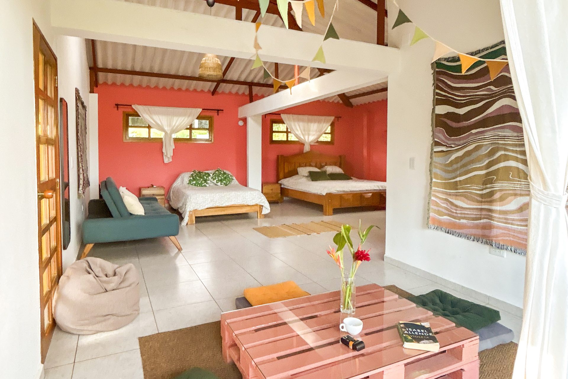 Sala de estar de la Suite King con mesa de centro y camas al fondo en El Nido Andino